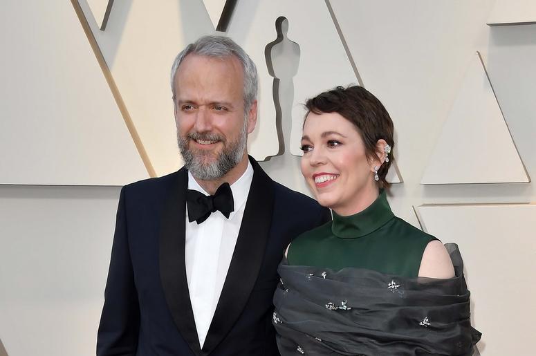 Olivia Coleman in Chopard earrings standing next to her husband. 
